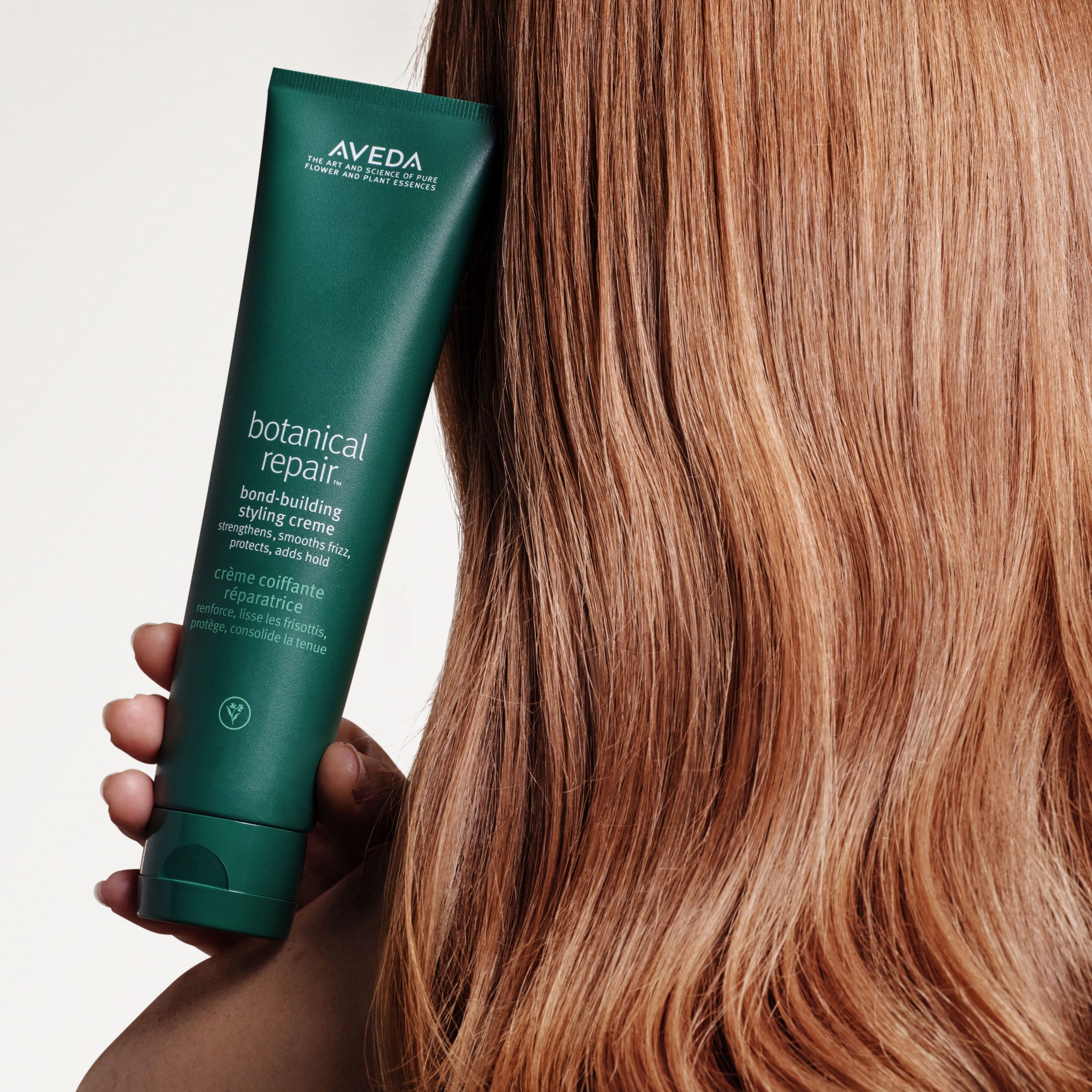 rejuvenation-spa-aveda-bond-building-aveda-plus-rewards-shop-aveda-image Picture of model with long blonde healthy hair holding the Aveda Botanical Repair Bond Building Treatment