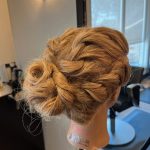Textured braided bun hairstyle on mannequin created by apprentice Chloe at Rejuvenation Spa.