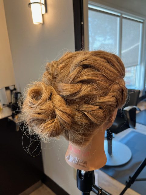Textured braided bun hairstyle on mannequin created by apprentice Chloe at Rejuvenation Spa.