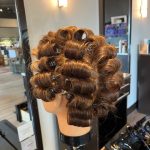 Mannequin head with a full curl set using Marcel irons, cleanly sectioned and pinned
