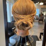 Back view of mannequin head with a soft braided bun updo created by apprentice Chloe during Week 8 at Rejuvenation Spa.