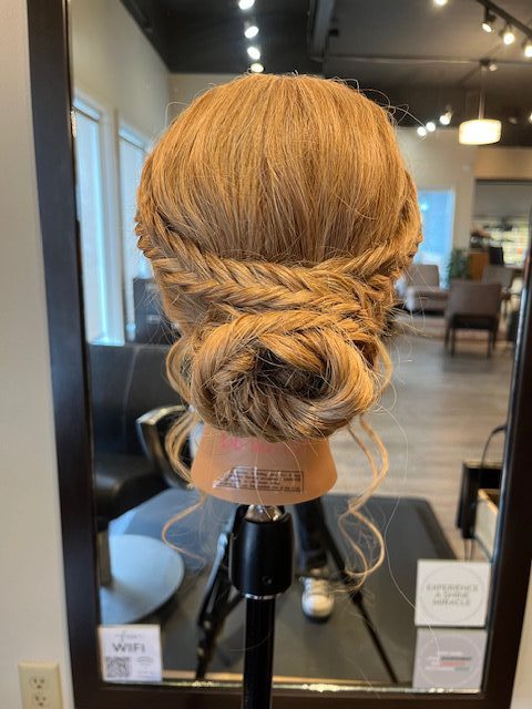 Back view of mannequin head with a soft braided bun updo created by apprentice Chloe during Week 8 at Rejuvenation Spa.