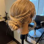 Mannequin head with a soft braided bun updo created by apprentice Chloe during Week 8 at Rejuvenation Spa.