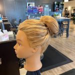 Mannequin head showing the right side of a Chignon updo with loose, textured twists created by apprentice Chloe.