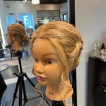Mannequin styled with an elegant updo featuring soft face-framing curls created by apprentice Chloe at Rejuvenation Spa.