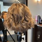 Blonde mannequin bob styled with curls after haircut.