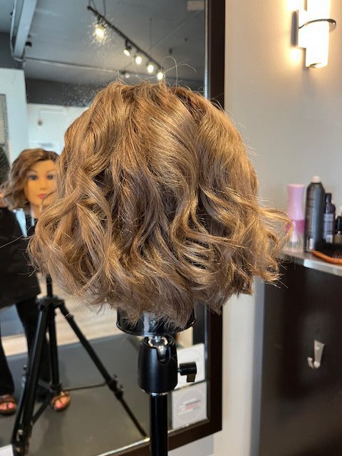 Blonde mannequin bob styled with curls after haircut.