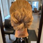 Mannequin head showing the back view of a loose braided bun updo.