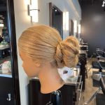 Mannequin showing a loose braid twisted into an open bun, left side view.