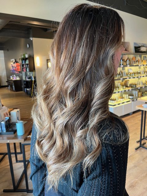 Long brunette hair styled in soft, flowing waves after a blowout using Aveda's new Abundant Blowout Volumizing Spray.