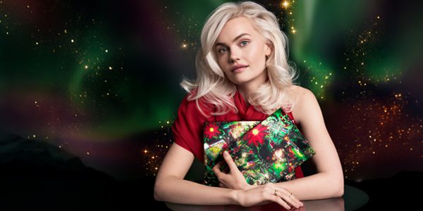 Aveda holiday model holding gift boxes with celestial Christmas background – Rejuvenation Spa October Specials